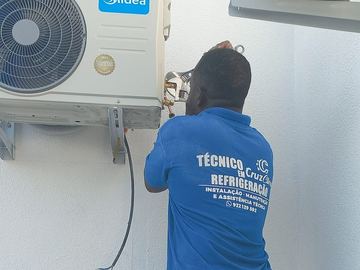 Técnico da Cruz Clima de costas a apertar as ligações de uma unidade exterior