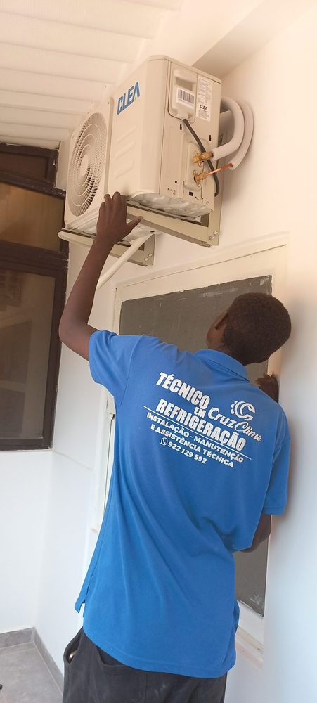 Técnico da Cruz Clima a montar uma unidade exterior na parede, visto de costas