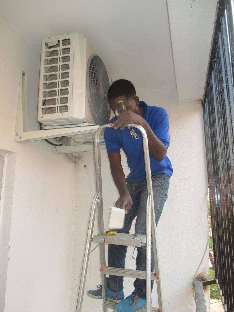 Técnico da Cruz Clima num escadote junto a uma unidade exterior montada num suporte de parede