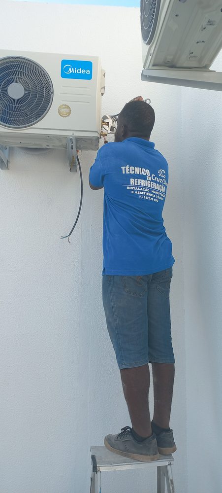 Técnico da Cruz Clima num escadote a ligar a tubagem de uma unidade exterior Midea