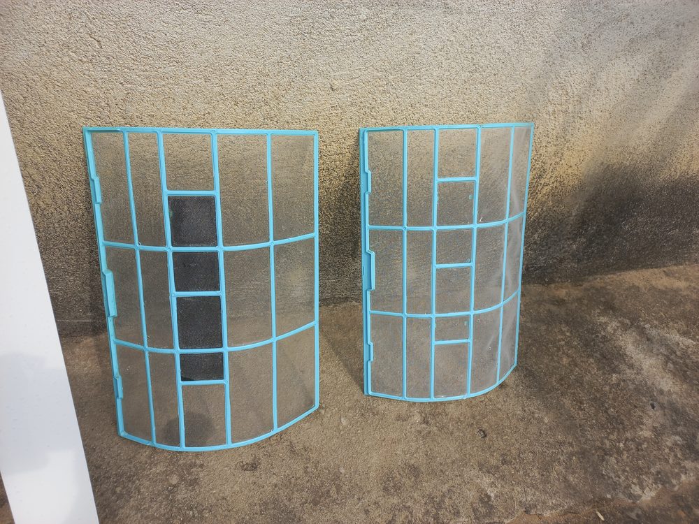 Dois filtros de ar condicionado limpos depois da lavagem, encostados a uma parede